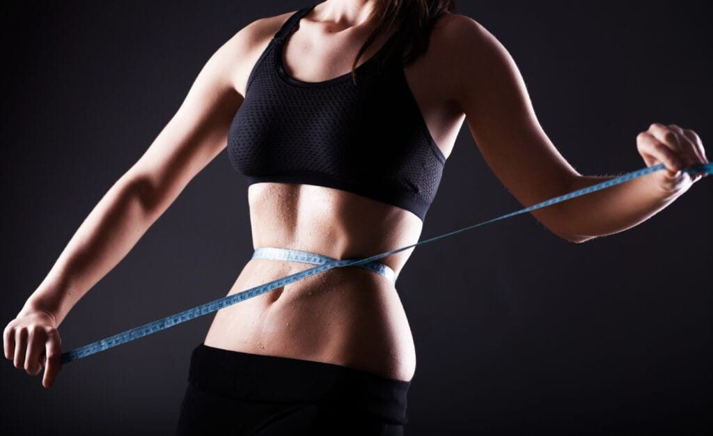Young fit woman measuring weight loss in Houston, TX | Vida Aesthetics And Wellness