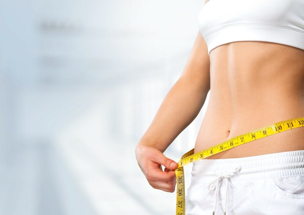 Young fit woman measuring weight loss in Houston, TX | Vida Aesthetics And Wellness