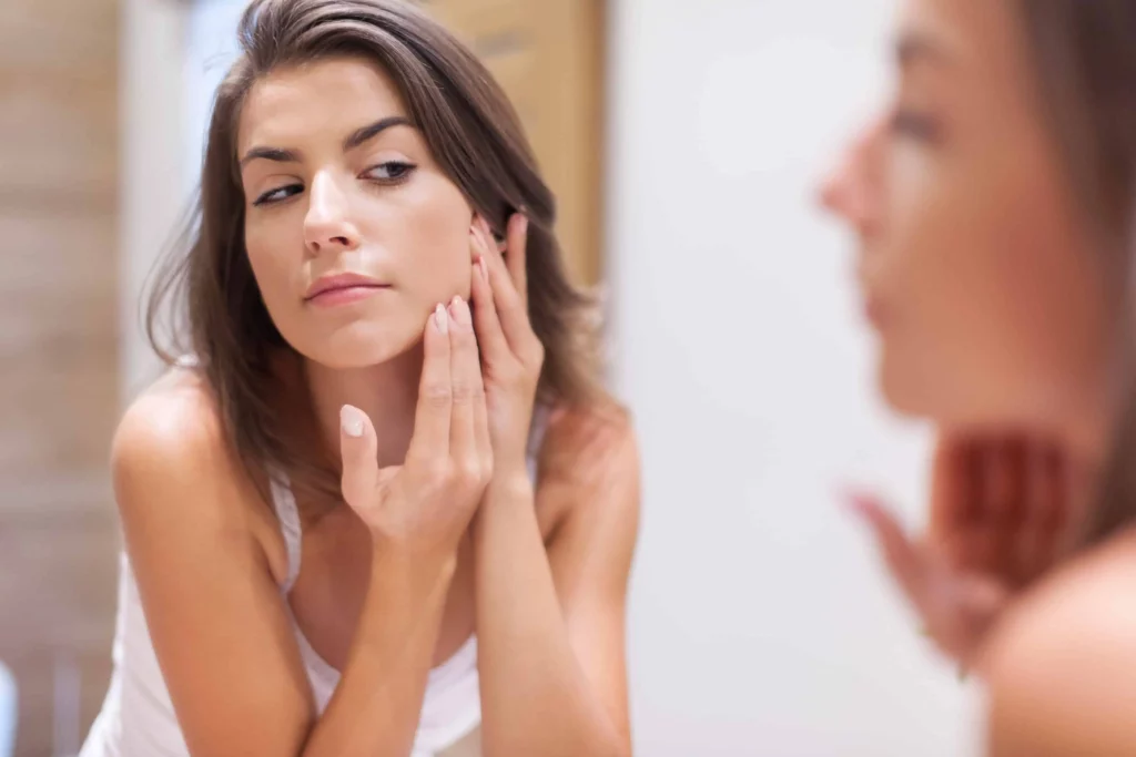Female checking her face in the mirror in Houston, TX | Vida Aesthetics And Wellness