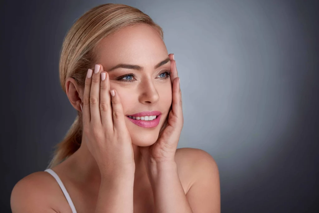 Smiling young female touching her face with both hand in Houston, TX | Vida Aesthetics And Wellness